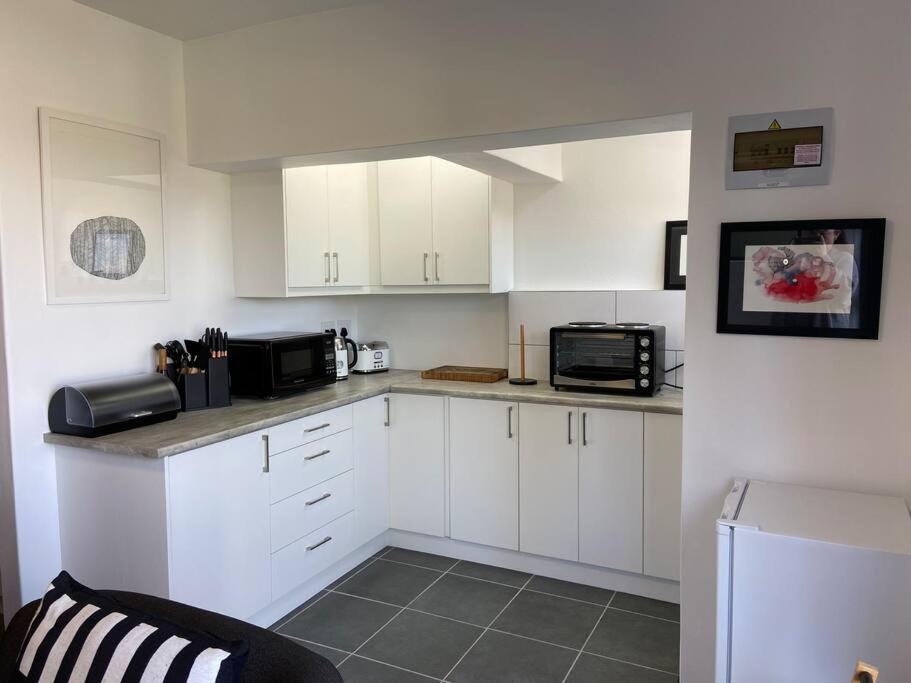 a kitchen with white cabinets and black appliances at 31Ridge Road in Durbanville