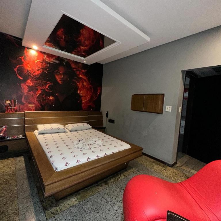 a bedroom with a bed and a painting on the wall at Motel Vitória Reggia in São Vicente
