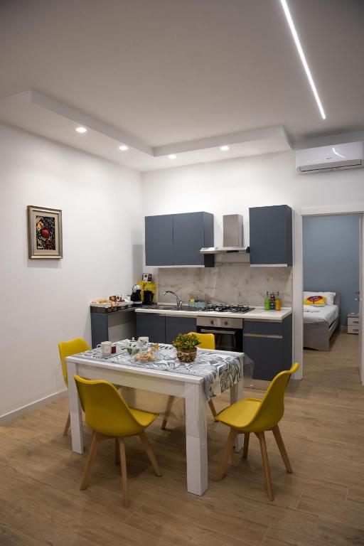 a kitchen with a white table and yellow chairs at Filo Apartment in Capua