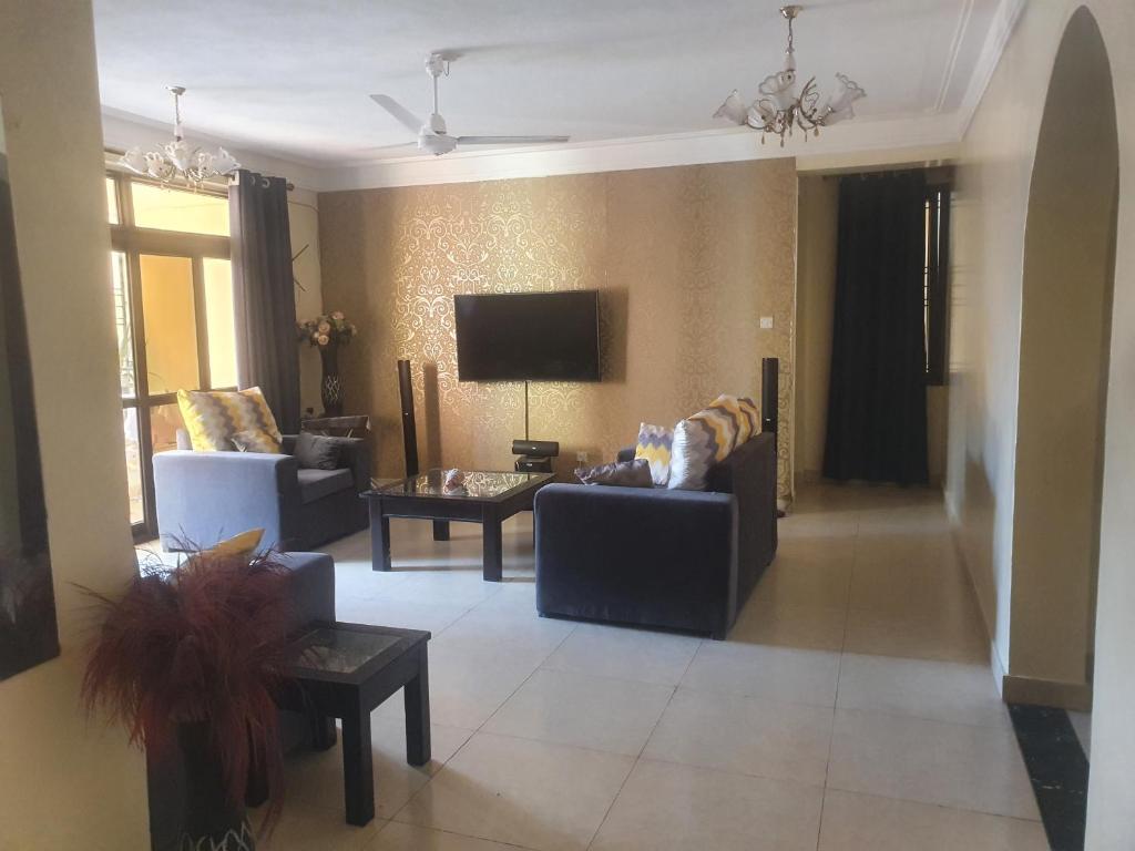 Una sala de estar con dos sofás y un televisor. en HOME TO STAY Apartments, en Mombasa