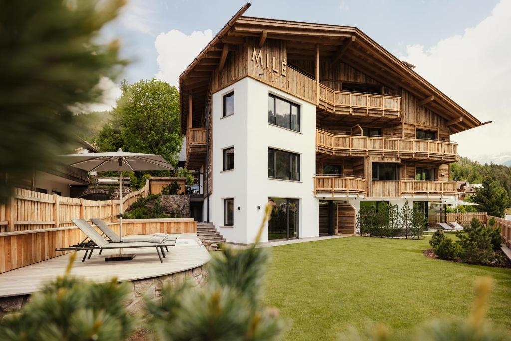 a large wooden house with a patio and a lawn at Luxury Chalet Milé in Ortisei
