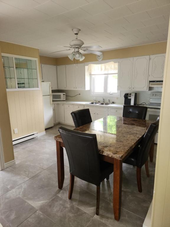 a kitchen with a wooden table and black chairs at Appartement de la rive in Shippagan
