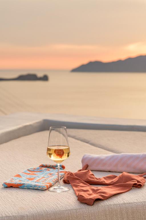 a glass of wine sitting on a table on the beach at Sunset Villa in Plaka Milou