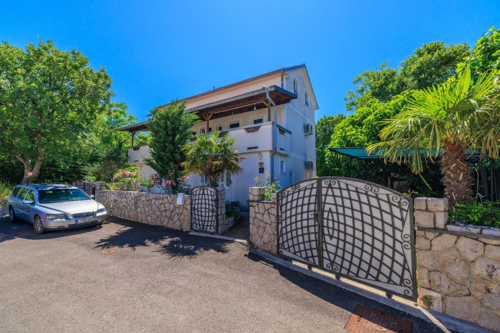 a car parked in front of a house with a fence at Apartment Lokvica in Omišalj