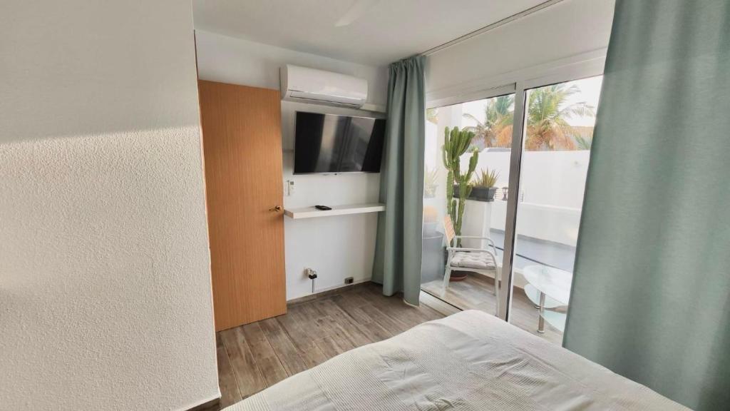 a bedroom with a bed and a tv and a window at Las Palmeras del Sol in Tarajalejo