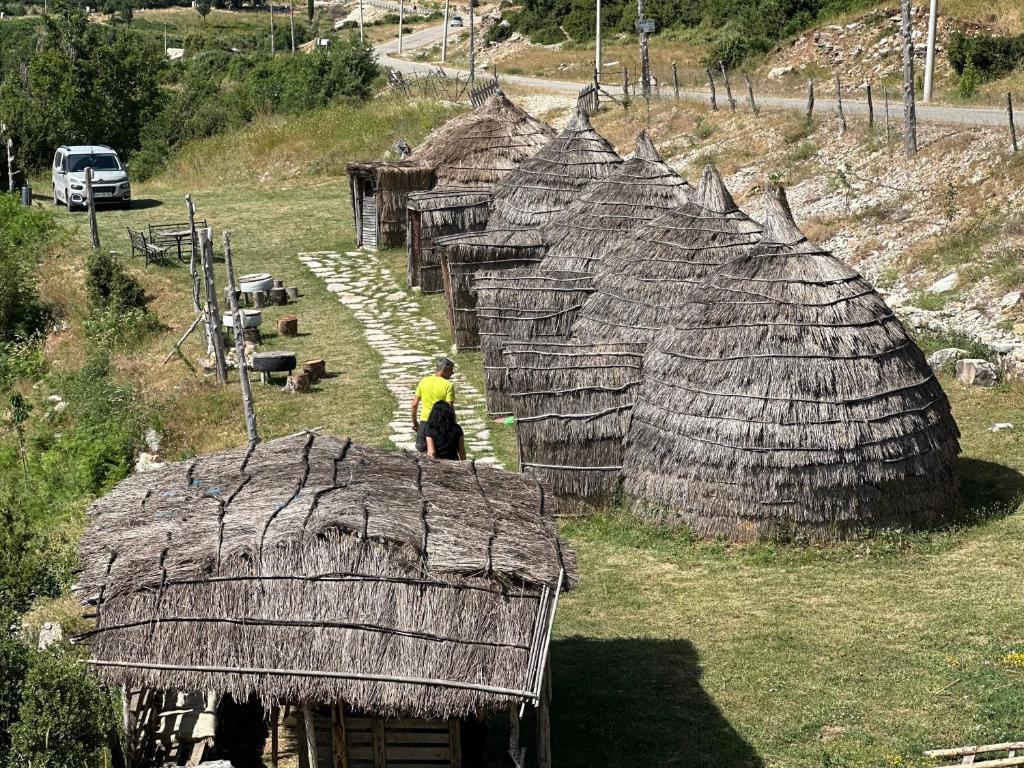 a man standing in front of a group of huts at Camping Lekdushi - Shehu in Tepelenë