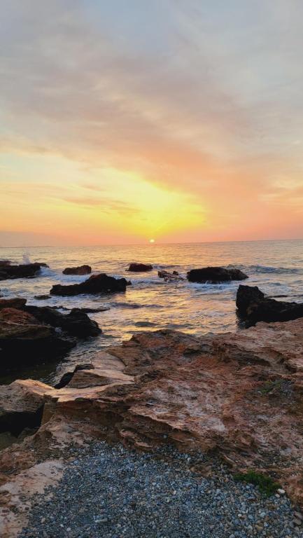 a sunset over the ocean with rocks in the water at Apartamento Torre la Sal in Cabanes