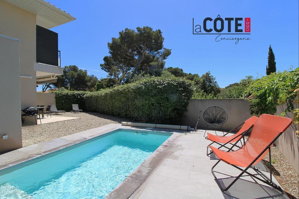 - une piscine avec une chaise rouge à côté d'une maison dans l'établissement Villa Palazzo - 6 couchages, à Sausset-les-Pins