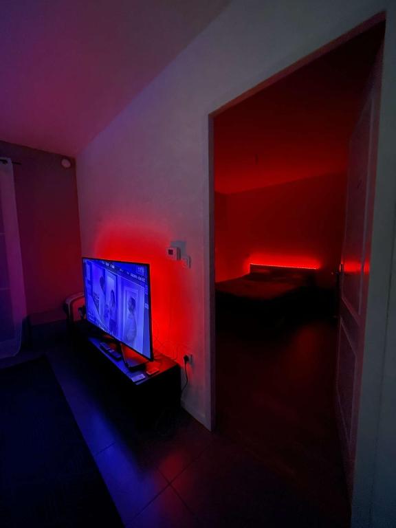 Cette chambre sombre dispose d'une télévision et de lumières rouges. dans l'établissement Appartement bordeaux proche de la plage, à Pont-de-la-Maye