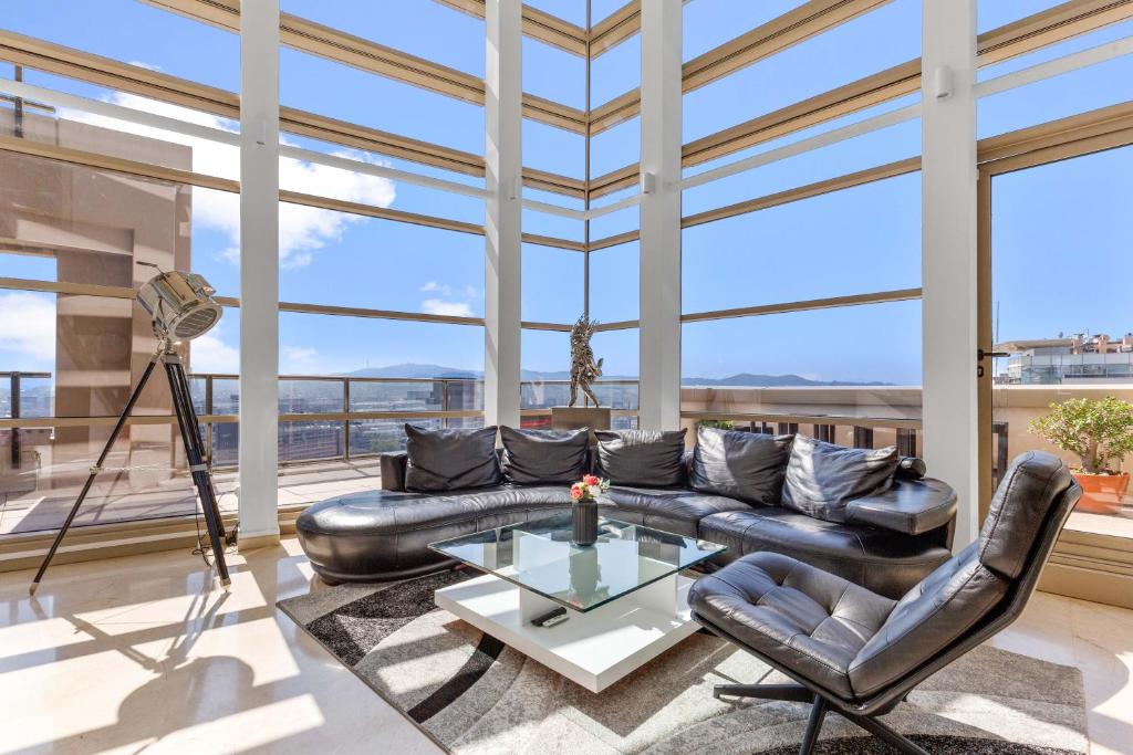 sala de estar con sofá de cuero y mesa de cristal en Penthouse Duplex with Epic Views, en Barcelona
