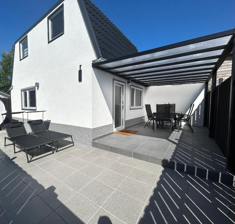 eine Terrasse mit Stühlen und einem Tisch und einem Gebäude in der Unterkunft Ferienvilla 10 Minuten vom Strand in Dirkshorn