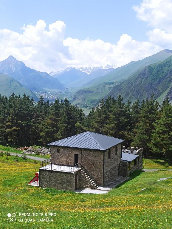 a building on a hill with mountains in the background at Crystal Kazbegi in Stepantsminda