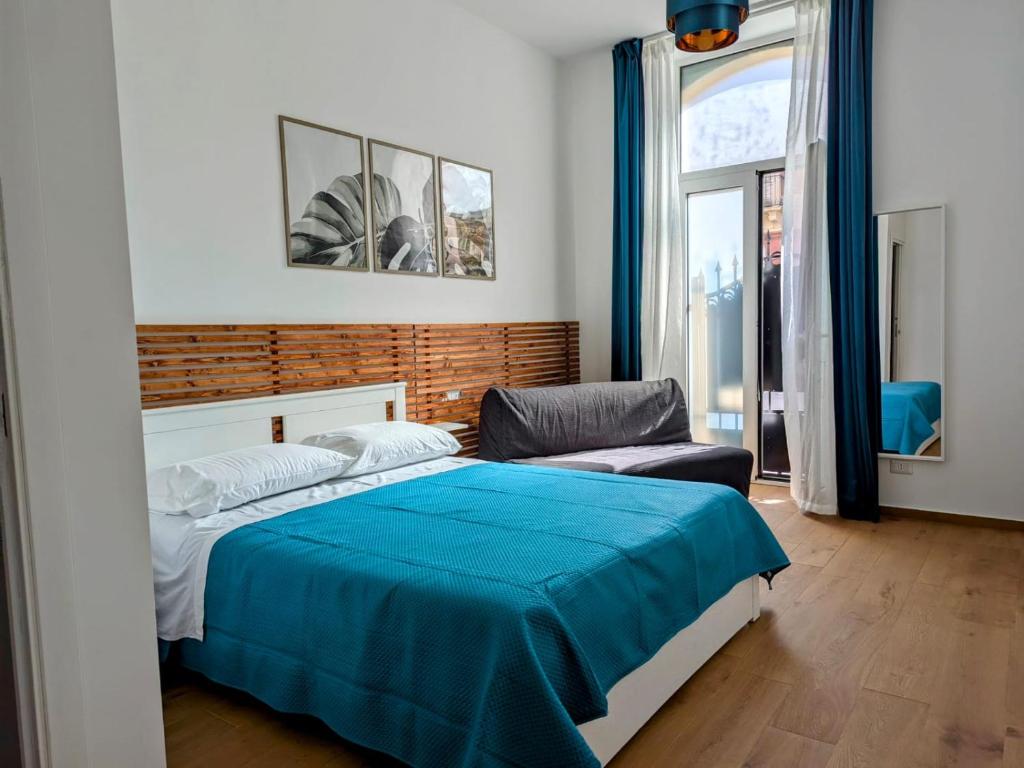- une chambre avec un lit bleu et un canapé dans l'établissement I Sogni Di Aretusa, à Syracuse