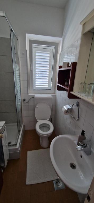 a white bathroom with a toilet and a sink at Palute in Supetar