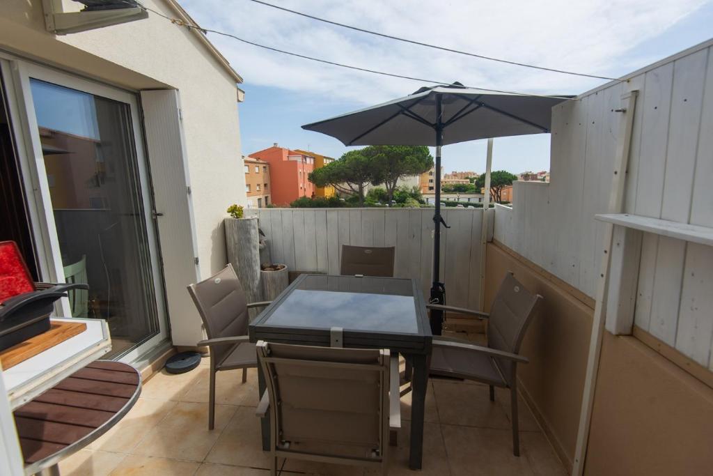 une table et des chaises avec un parasol sur un balcon dans l'établissement Appartement Confort 57 m2 avec terrasse parking couvert, au Cap d'Agde