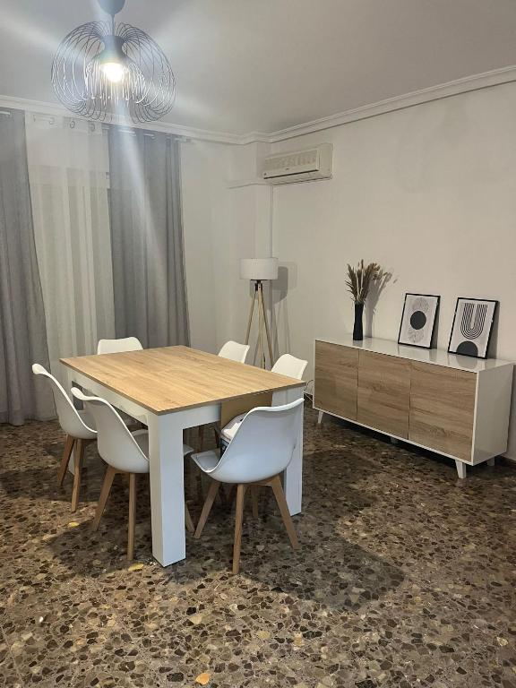 a dining room table with white chairs and a dresser at Apartamento Mágina in Mancha Real