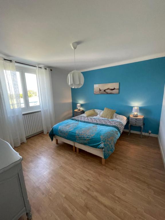 une chambre avec un lit avec un mur bleu dans l'établissement Maison location saisonniere, à Trouguennour