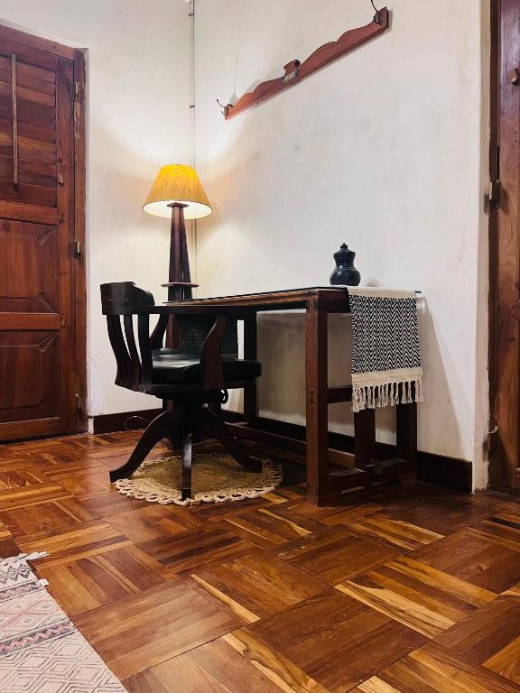 a room with a desk with a chair and a lamp at Svarna in Udupi