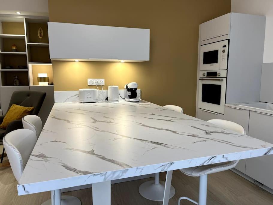 a kitchen with a marble table and white appliances at La Villa du Soleil in Saint-Cyprien