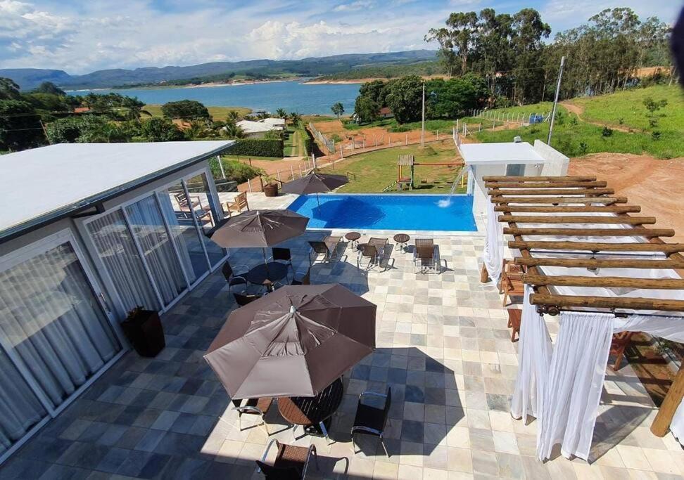 een patio met tafels en parasols en een zwembad bij Mirante Mar de Minas - Casa para Temporada Lago de Furnas pertinho dos Canyons in São José da Barra