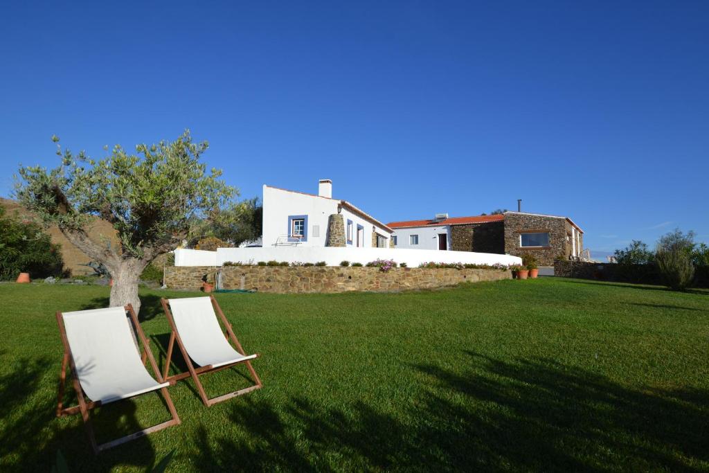 two chairs sitting in the grass in front of a house at Casa dos Castelejos in Guerreiro