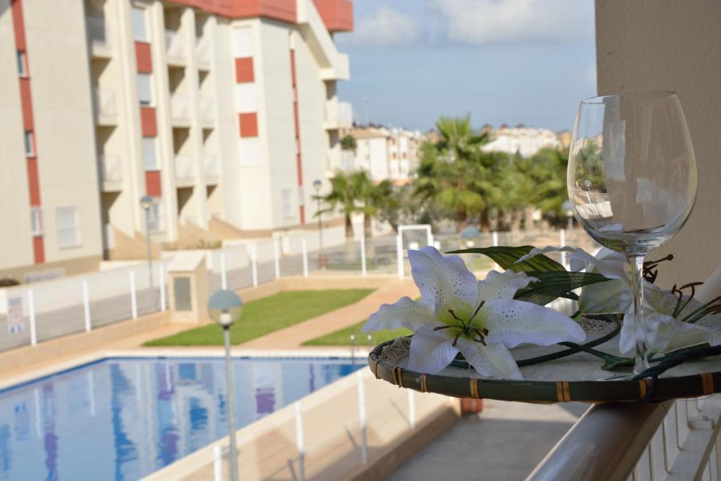 a table with a wine glass and flowers on a balcony at El apartamento de Mamá - Cabo Roig in Playas de Orihuela