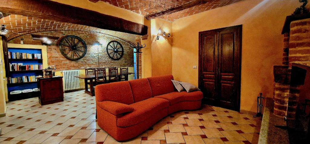 een woonkamer met een rode bank en een bakstenen muur bij Monferrato AgriCottage Valentina in Calliano