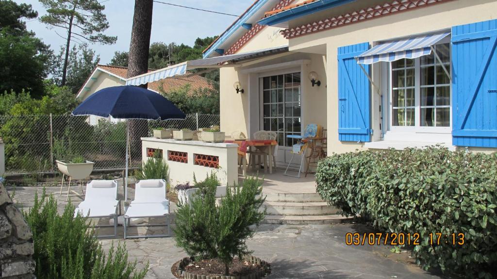 une maison avec un parasol, des chaises et une table dans l'établissement La Sirène Escapade en famille ou entre amis Maison lumineuse avec extérieur privé à 5 min de la plage Confort et convivialité assurés, à Saint-Trojan-les-Bains