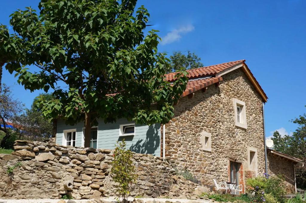 an old stone house with a stone wall at Le Poulailler in Blesle