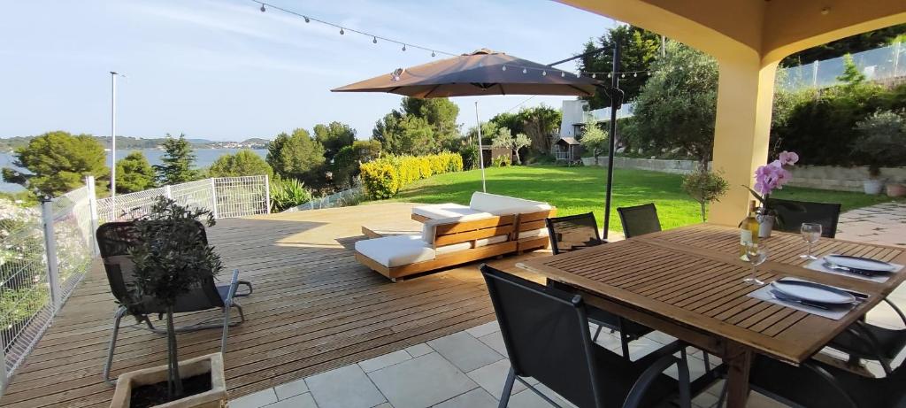 une terrasse en bois avec une table, des chaises et un parasol dans l'établissement Istres villa spacieuse , vue imprenable, à Istres