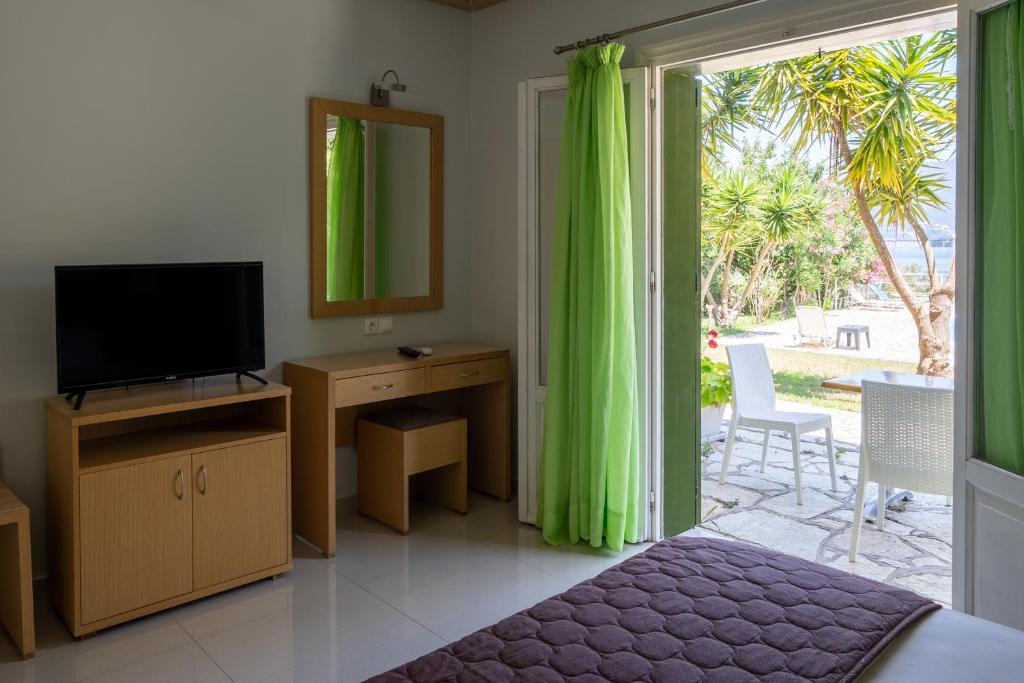 salon z telewizorem i przesuwnymi szklanymi drzwiami w obiekcie Vliho Bay Suites & Apartments w mieście Yénion