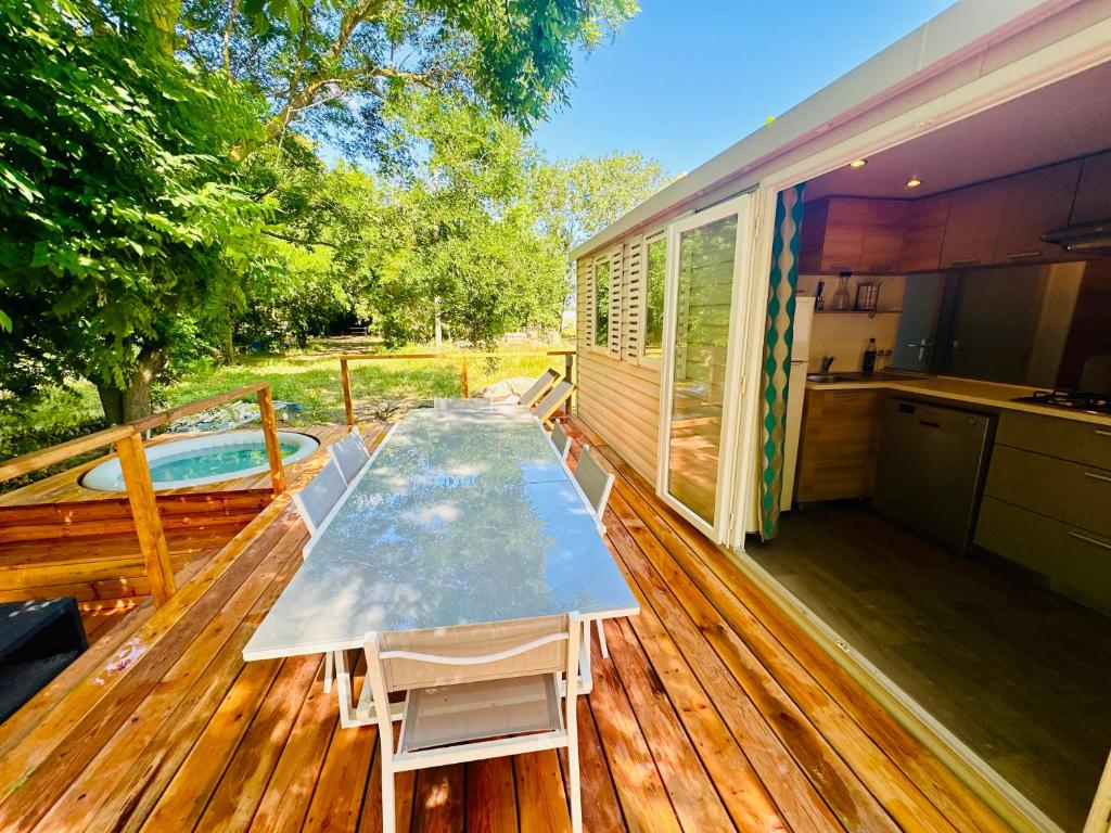 une terrasse en bois avec une table et une cuisine dessus dans l'établissement Cottage Domaine Privé - Sud de France - Jacuzzi, à Le Cailar