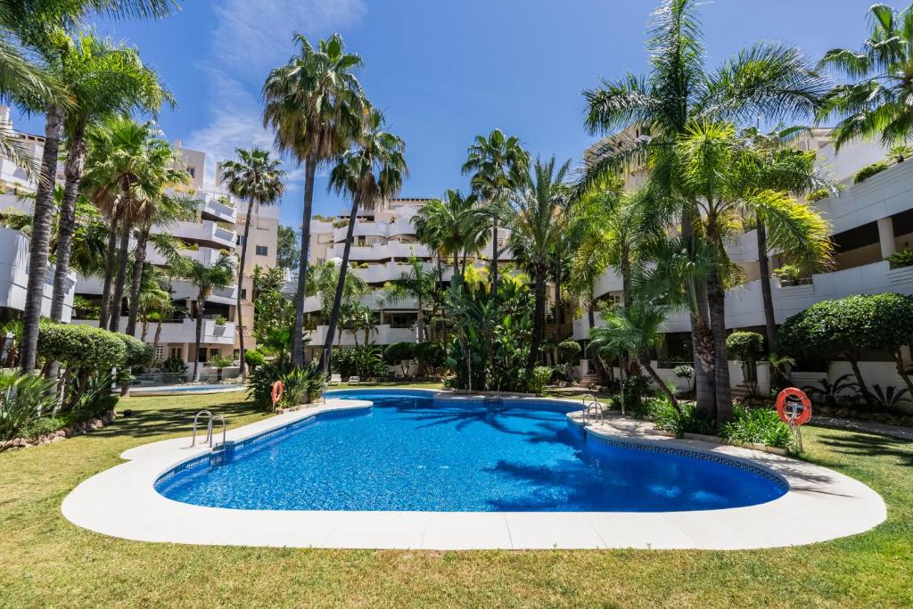 a swimming pool in front of a building with palm trees at Molo Residences Boutique Apartments & Spa in Marbella