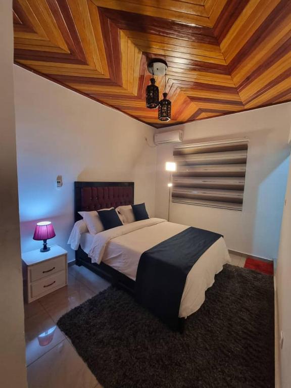 a bedroom with a large bed with a wooden ceiling at Baobab Lodge Douala - Makepe in Douala