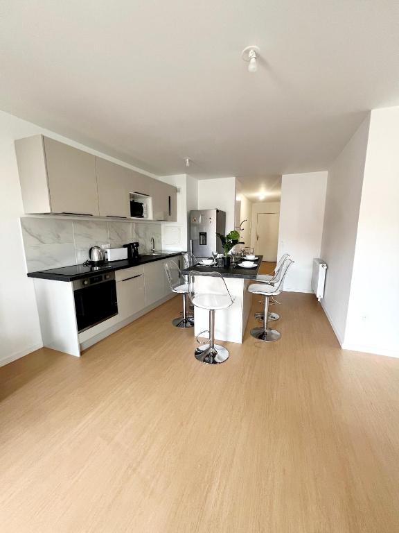 une cuisine avec des armoires blanches et une table et des chaises dans l'établissement Idéal emplacement à Drancy, à Drancy