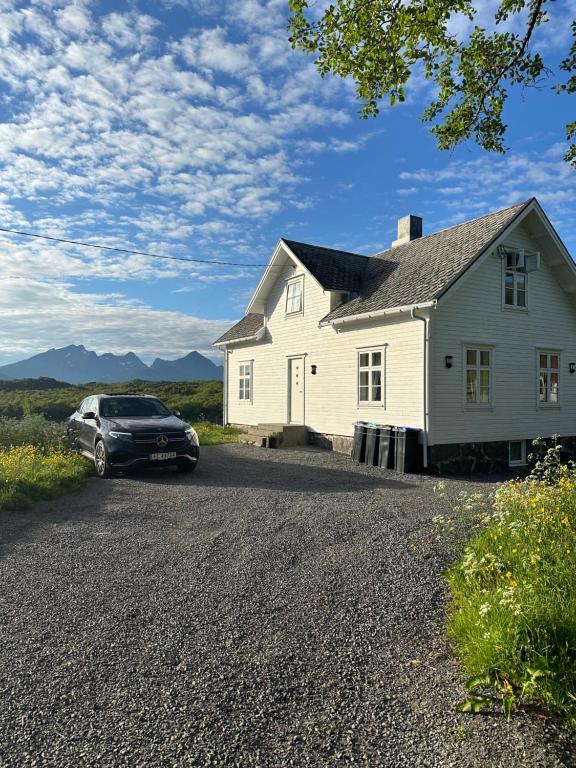 a car parked in front of a white house at Nordlandshus Lofoten in Berg