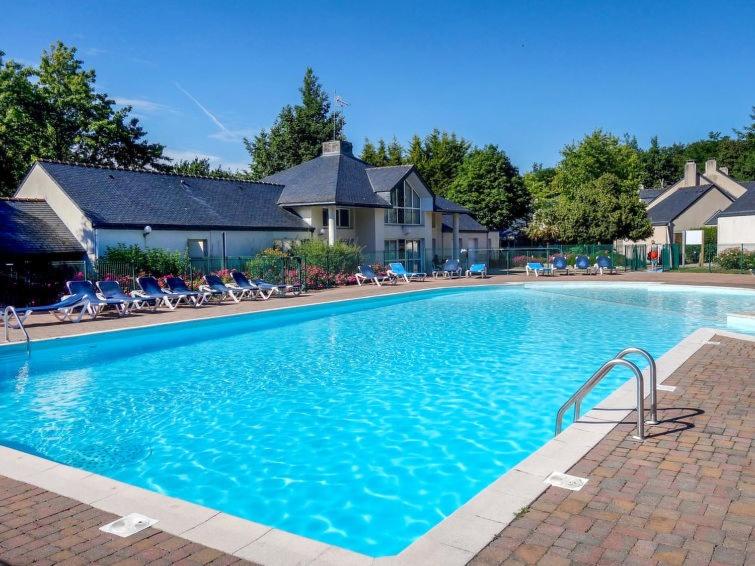 a large blue swimming pool in front of a house at Cottage du Golf en Morbihan in Ploemel