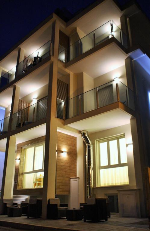 a large building with chairs in front of it at night at Hotel Villa Enea in Cattolica
