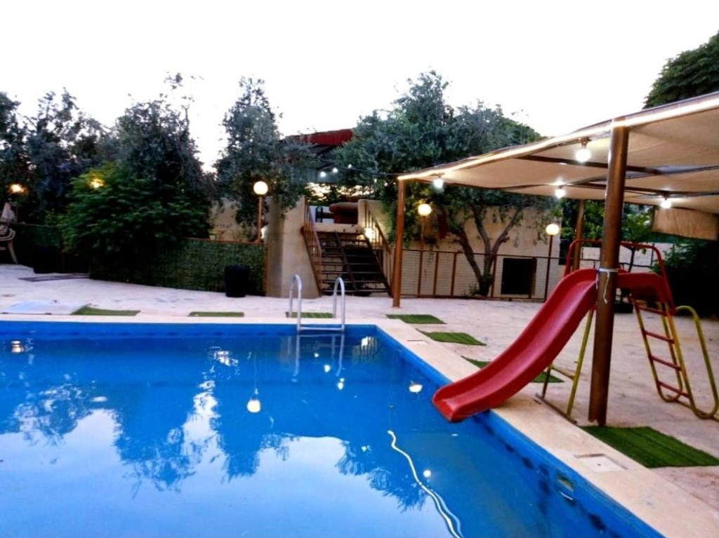 a swimming pool with a slide and a playground at مزرعة وشاليه السلطانة مرج الحمام in Al Baḩḩāth
