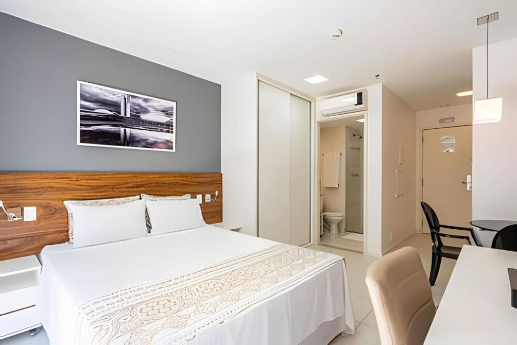 1 dormitorio con 1 cama blanca, mesa y sillas en Hotel FUSION, en Brasilia