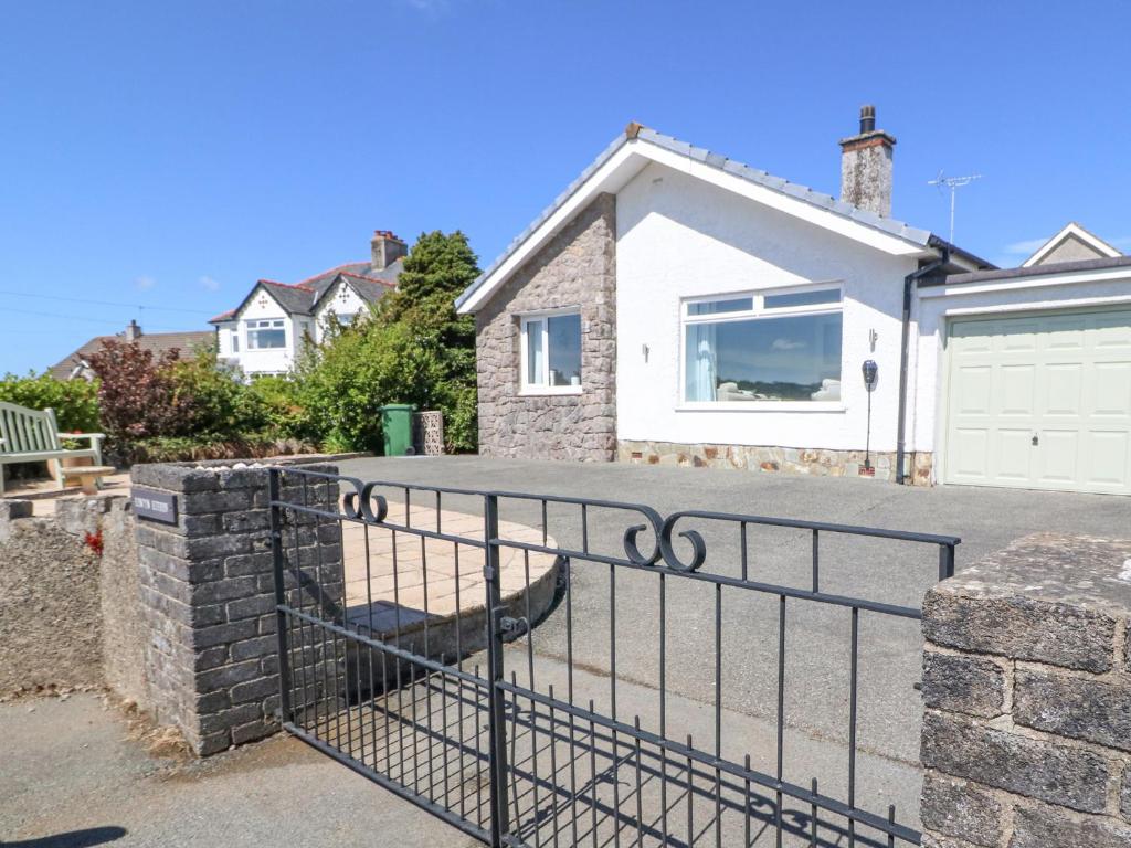 a fence in front of a house with a garage at Llwyn Eithin in Benllech