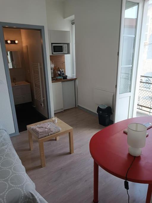 un salon avec une table rouge et une cuisine dans l'établissement Studio avec balcon, à Pau