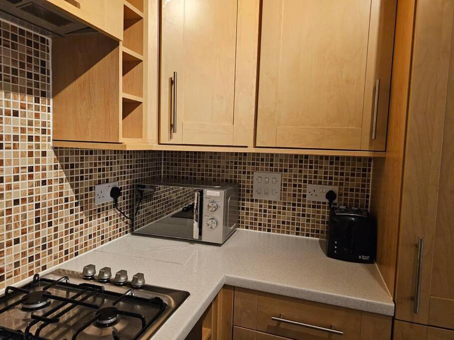 a kitchen with a stove and a microwave at The Park view, 2 Bedroom House in Kirkcaldy