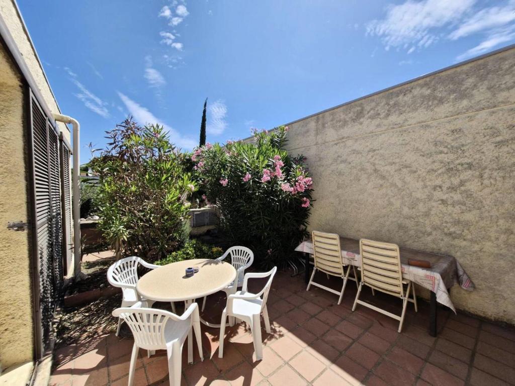 - une terrasse avec une table, des chaises et des fleurs dans l'établissement Résidence LE GINESTOU - Maisons & Villas pour 4 Personnes 24, à Port-Leucate