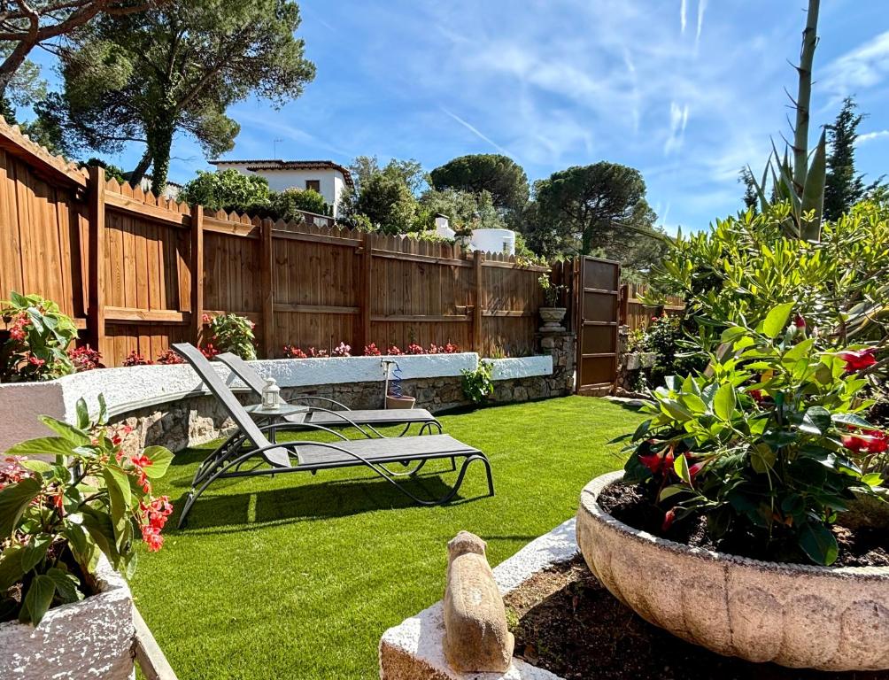a garden with a chair and some plants and a fence at Cala Canyelles Villa & Private Studio with Garden in Lloret de Mar