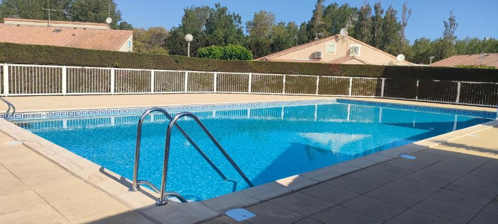 une piscine avec de l'eau bleue dans une cour dans l'établissement Maison Bord de mer Vendres-Plage Valras-Plage, à Vendres
