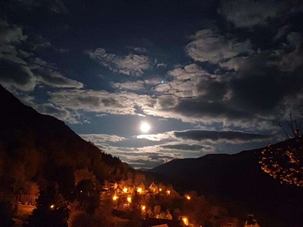 une pleine lune se levant sur une ville de montagne la nuit dans l'établissement Studio Indépendant dans Demeure Typique d'Exception, à Saint-Vincent