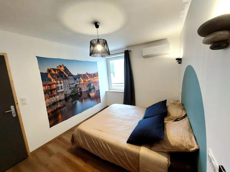 ein Schlafzimmer mit einem Bett und einem Gemälde an der Wand in der Unterkunft Le Caladou ! T3 classé 3 étoiles - Centre ville in Espalion