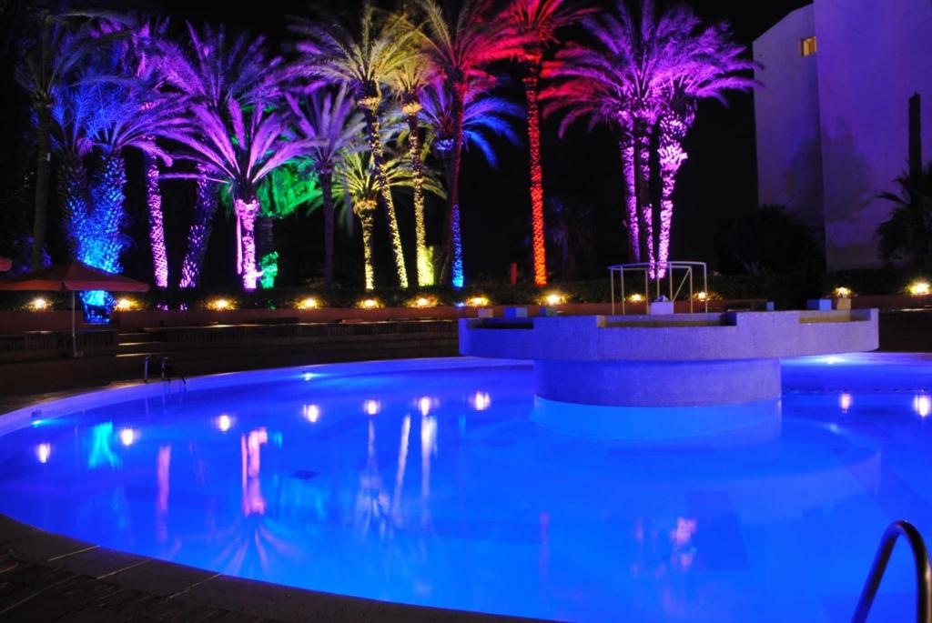 a pool with palm trees lit up at night at HAMILTON Agadir in Agadir