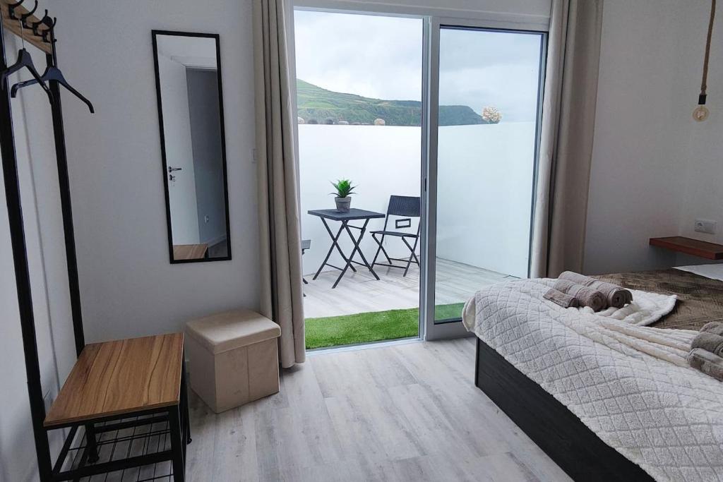ein Schlafzimmer mit Bett und Blick auf einen Balkon in der Unterkunft Azure Loft in Mosteiros